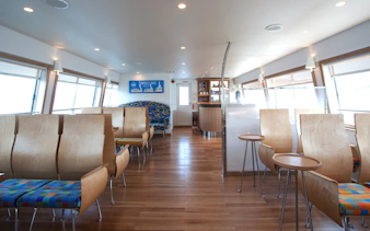 Interior seating area of Lake Yamanaka Swan Lake cruise ship with wooden chairs and tables.