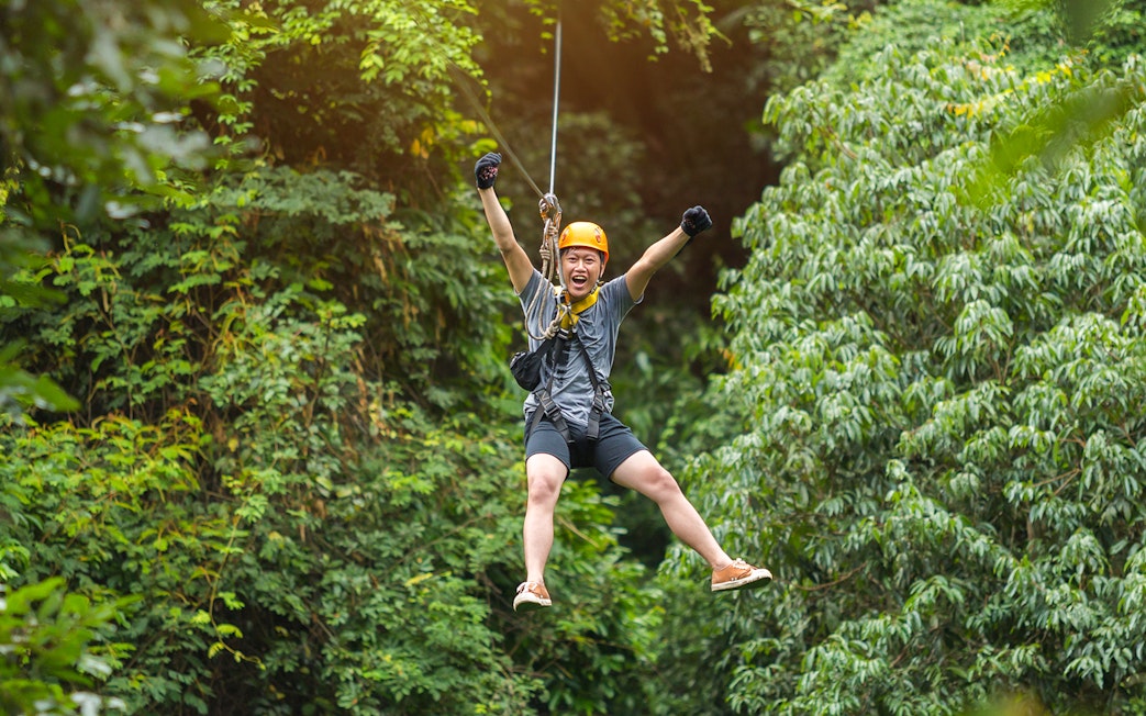 Man ziplining through lush forest at Hanuman World Phuket.