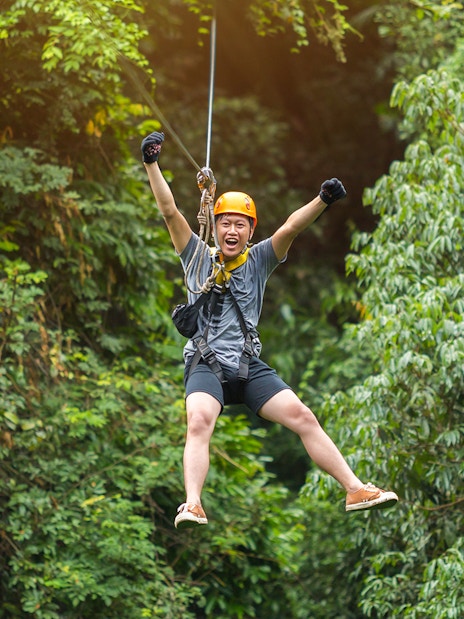 Man ziplining through lush forest at Hanuman World Phuket.