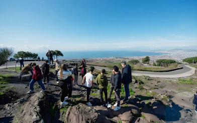 Group hiking at Vesuvius National Park with view of Naples, Italy in the background.