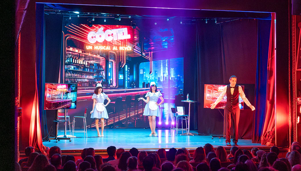 Stage performance of "Coctel, un Musical al reves" with actors in a bar setting.