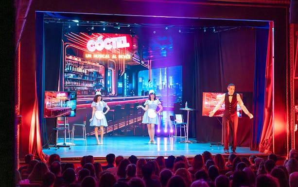 Stage performance of "Coctel, un Musical al reves" with actors in a bar setting.