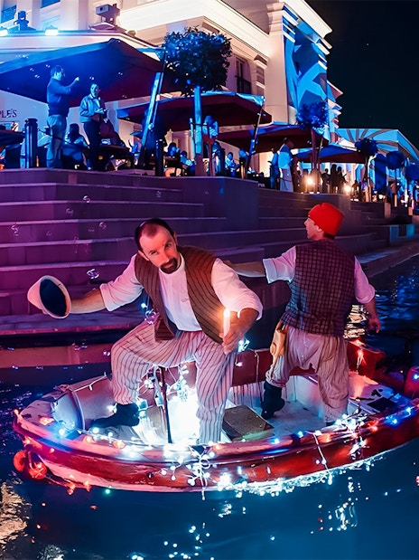 Boat parade at Land of Legends Night Show with performers on illuminated canal.