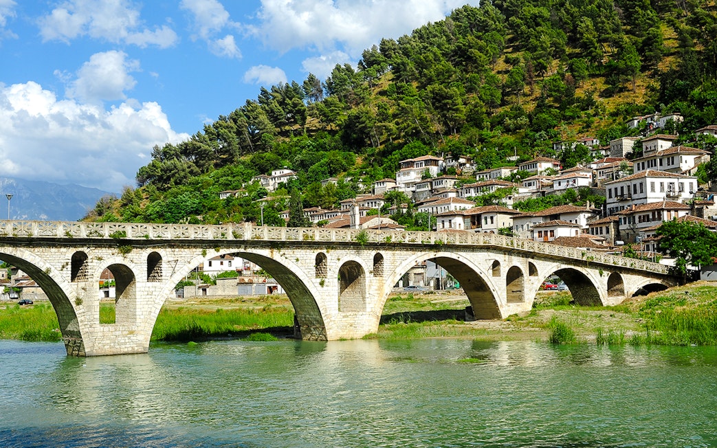 Gorica Bridge spanning river with hillside houses in Berat, Albania.