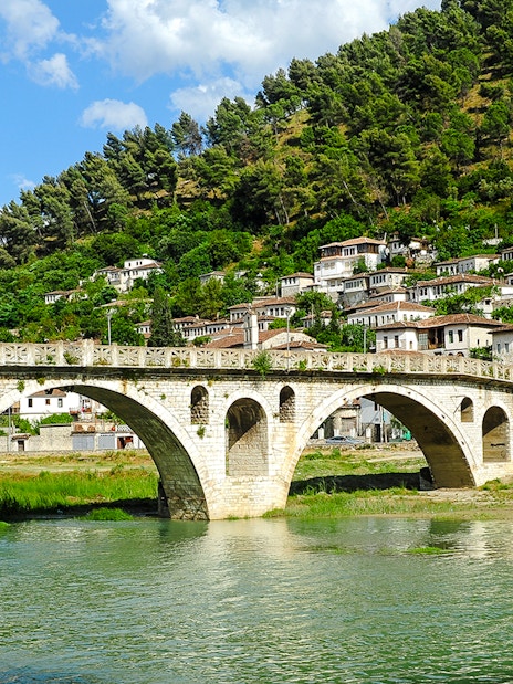 Gorica Bridge spanning river with hillside houses in Berat, Albania.