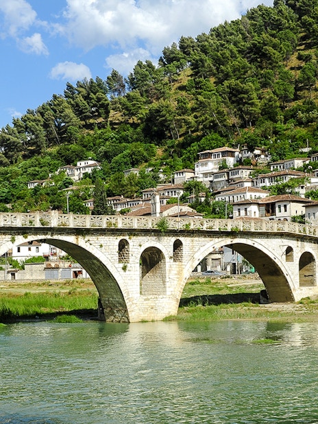 Gorica Bridge spanning river with hillside houses in Berat, Albania.