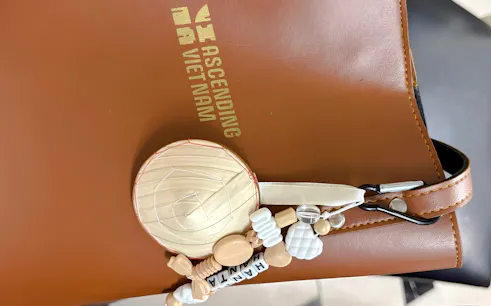 Vietnamese mini hat keychain with beads on a brown leather bag, Hanoi.