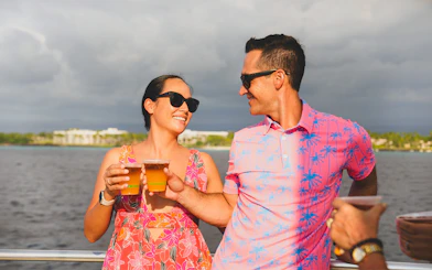 Couple enjoying drinks on Waikiki Signature Sunset Sail with ocean view.