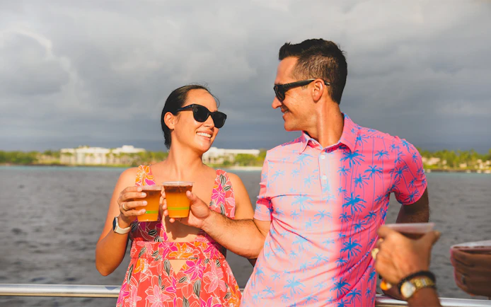 Couple enjoying drinks on Waikiki Signature Sunset Sail with ocean view.