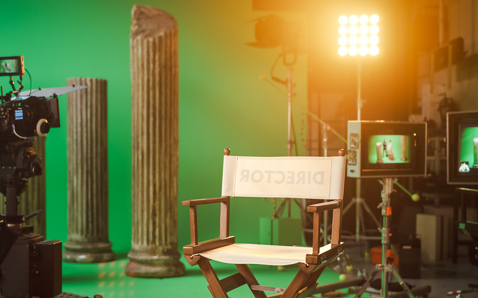 Film studio set with director's chair, camera, and ancient column props.