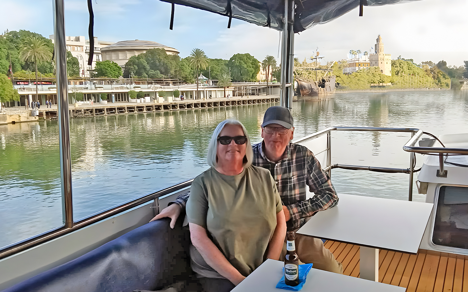 Tourists enjoying a cruise on the Guadalquivir River in Seville with Torre del Oro in view.