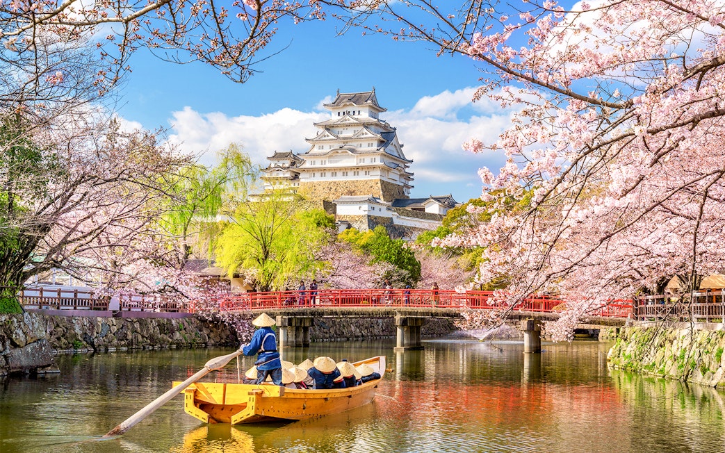 Osaka Castle with cherry blossoms and a boat on the moat, skip-the-line tickets available.
