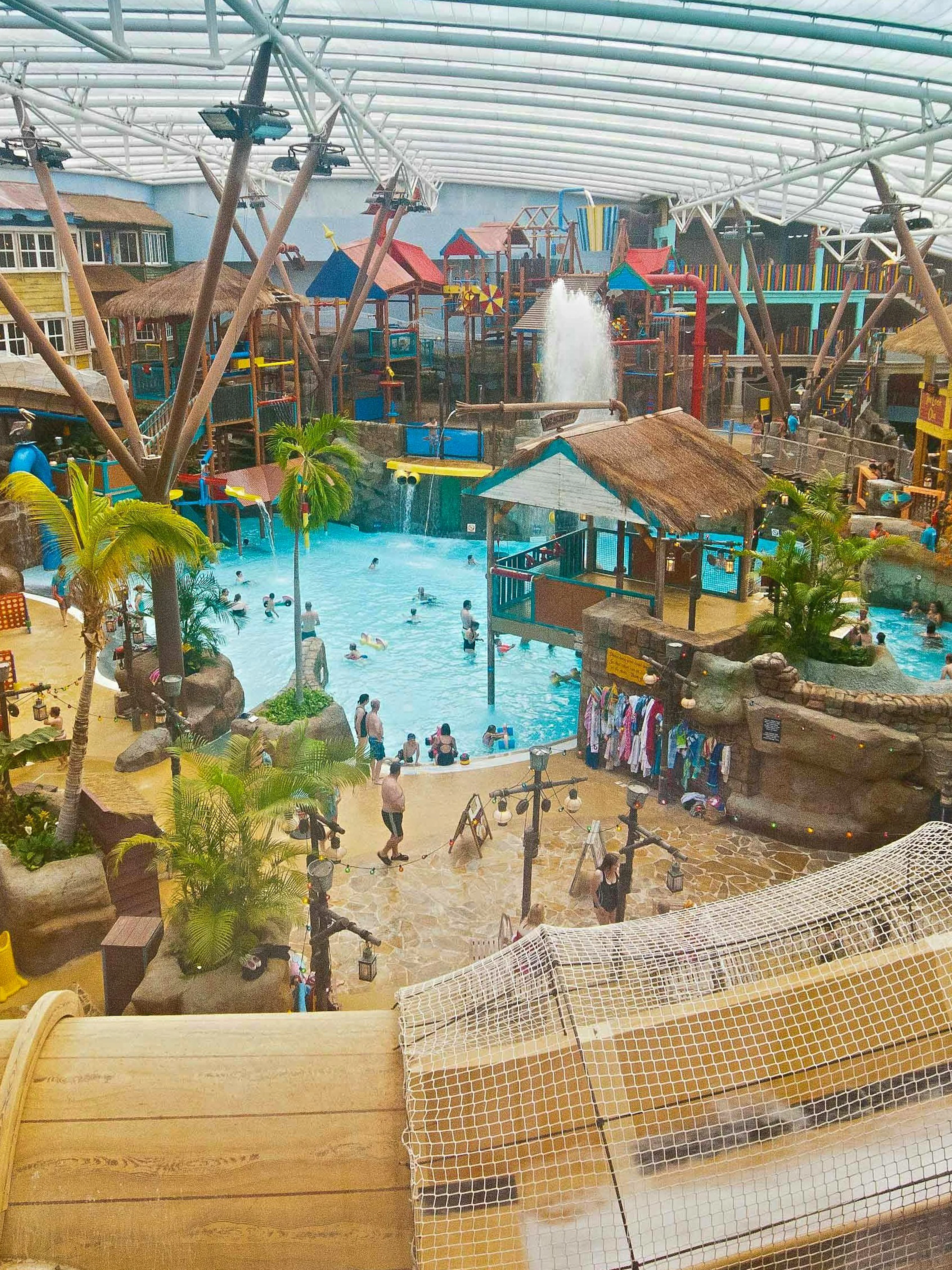 Indoor waterpark with slides and pools at Alton Towers, UK, featuring tropical decor and visitors enjoying activities.