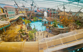 Indoor waterpark with slides and pools at Alton Towers, UK, featuring tropical decor and visitors enjoying activities.
