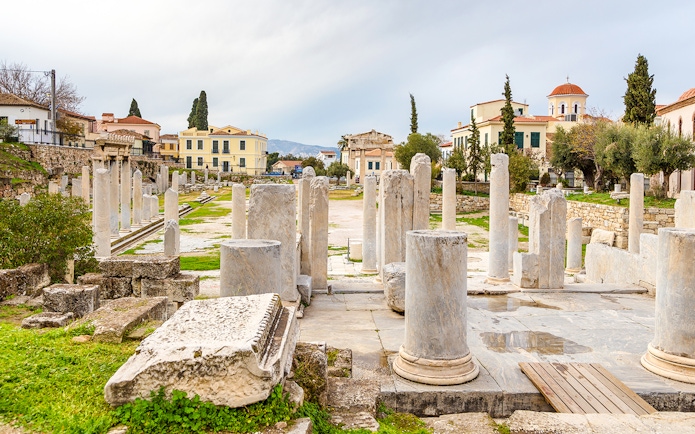 Roman Agora ruins with columns in Athens, Greece, surrounded by historic buildings.