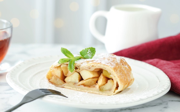 Slice of apple strudel on a plate with mint garnish, Vienna, Austria.
