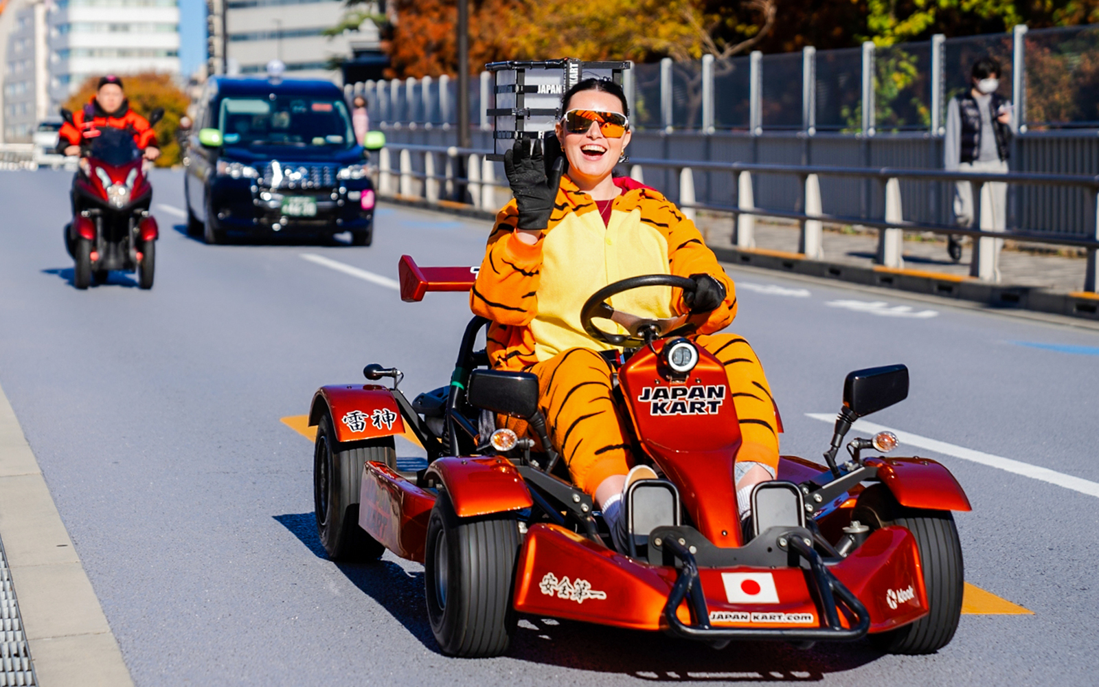 Person in tiger costume driving go-kart on Shibuya street, Tokyo.