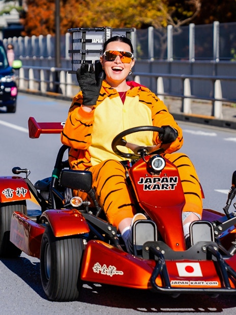 Person in tiger costume driving go-kart on Shibuya street, Tokyo.