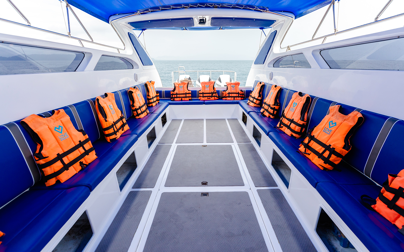 Interior of speed boat with blue seating and orange life jackets.