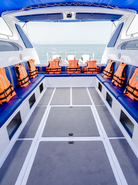 Interior of speed boat with blue seating and orange life jackets.