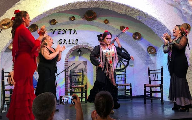 Flamenco dancer performing at Venta el Gallo with musicians and audience.