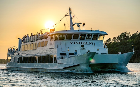 Swedish Fika boat cruising through Stockholm Archipelago at sunset.