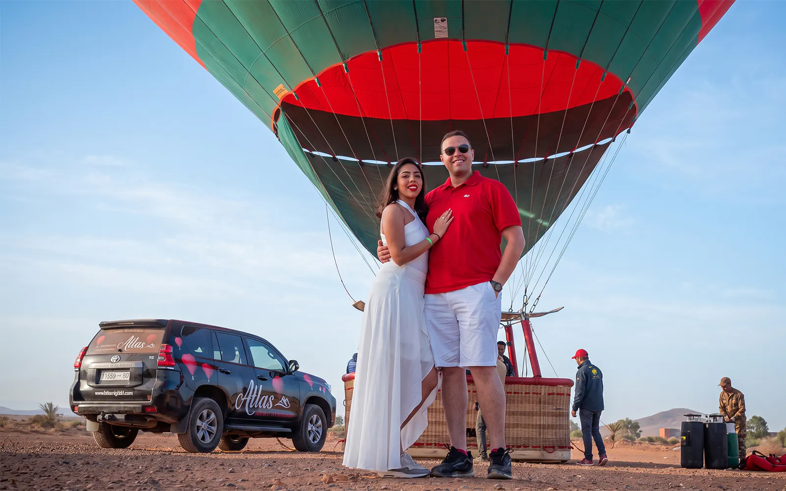 Couple standing in front of a hot air balloon in Marrakesh desert, ready for sunrise flight.