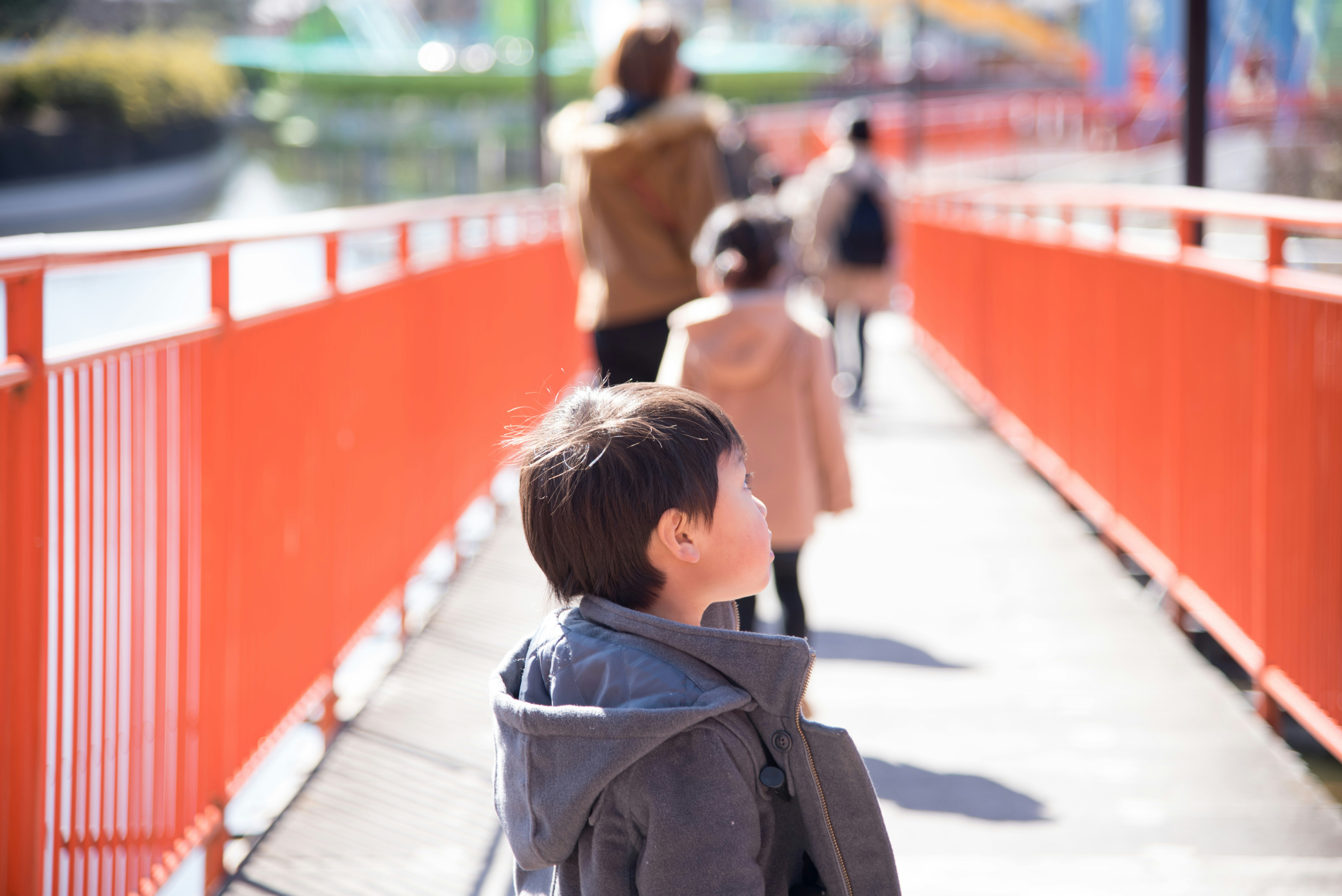 Child walking on a bridge towards a theme park entrance.