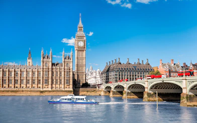 Thames River cruise boat near Big Ben and Westminster Bridge, London.