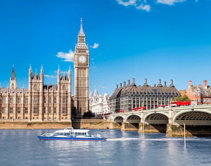 Thames River cruise boat near Big Ben and Westminster Bridge, London.