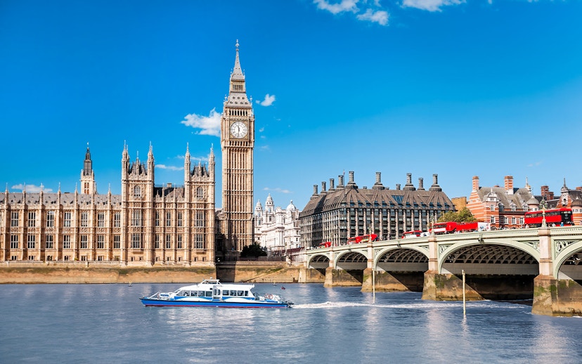 Thames River cruise boat near Big Ben and Westminster Bridge, London.