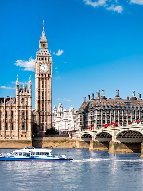Thames River cruise boat near Big Ben and Westminster Bridge, London.