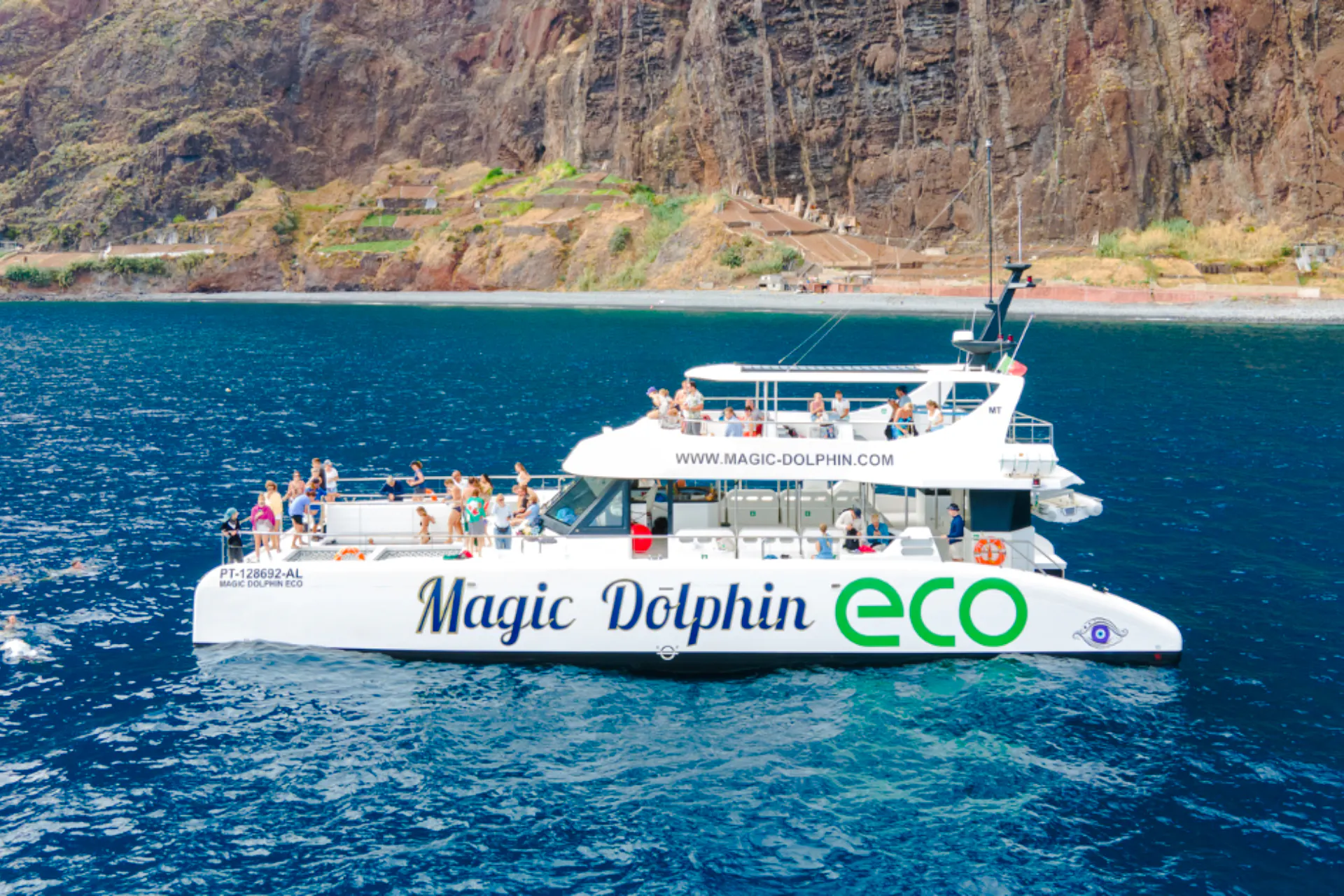 Catamaran tour with passengers near Madeira cliffs.