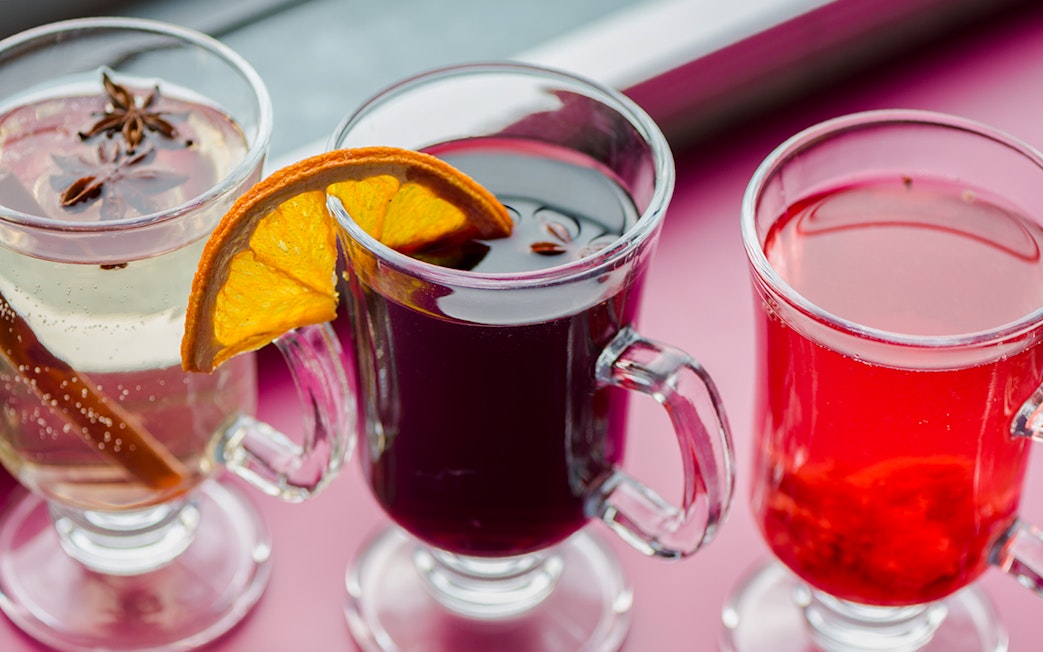 Three glasses of mulled wine with spices and orange slices on a Danube River nighttime sightseeing cruise.