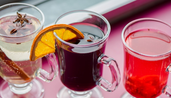 Three glasses of mulled wine with spices and orange slices on a Danube River nighttime sightseeing cruise.