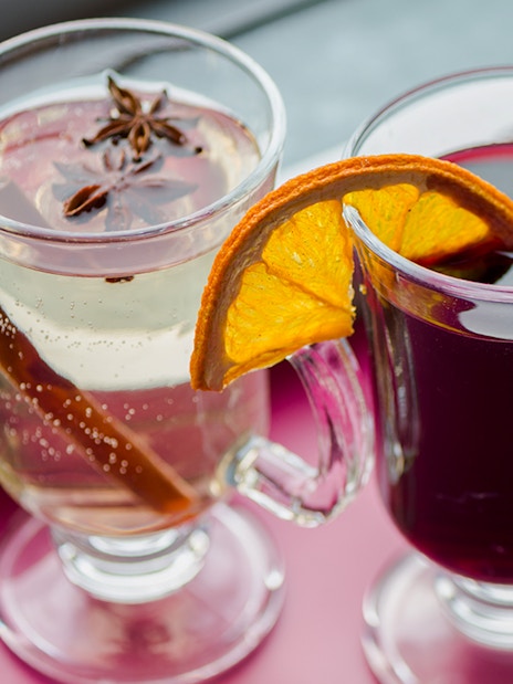 Three glasses of mulled wine with spices and orange slices on a Danube River nighttime sightseeing cruise.
