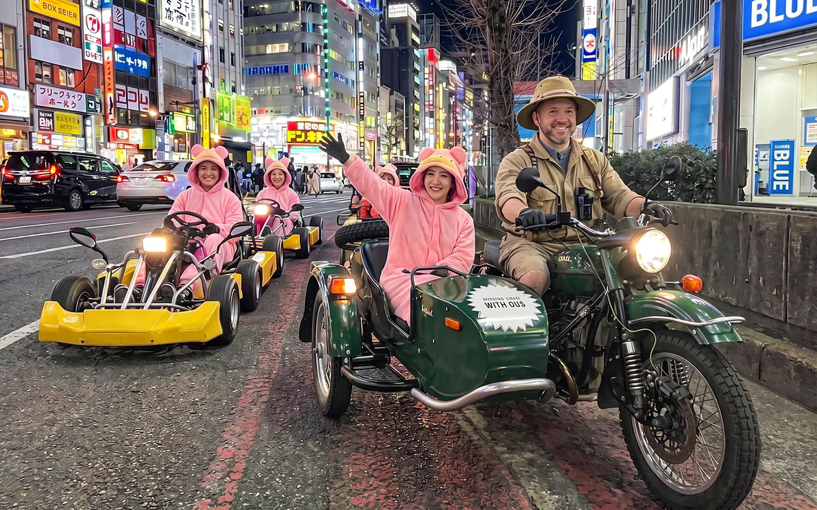 Go-kart riders in pink costumes on Tokyo street during Banana Kart tour from Shinjuku to Shibuya.