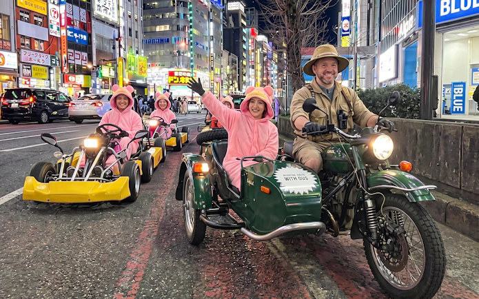Go-kart riders in pink costumes on Tokyo street during Banana Kart tour from Shinjuku to Shibuya.
