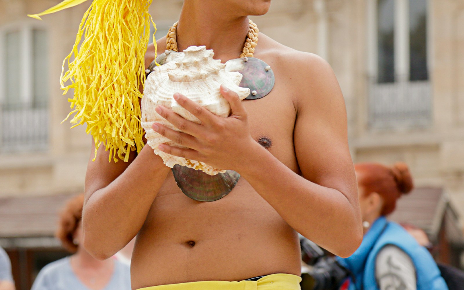 Hula dancer holding a conch shell, preparing to blow it.