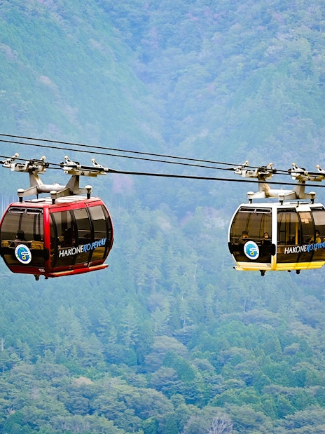 Hakone ropeway gondolas over lush green mountains in Japan.
