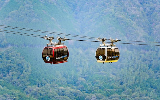 Hakone ropeway gondolas over lush green mountains in Japan.