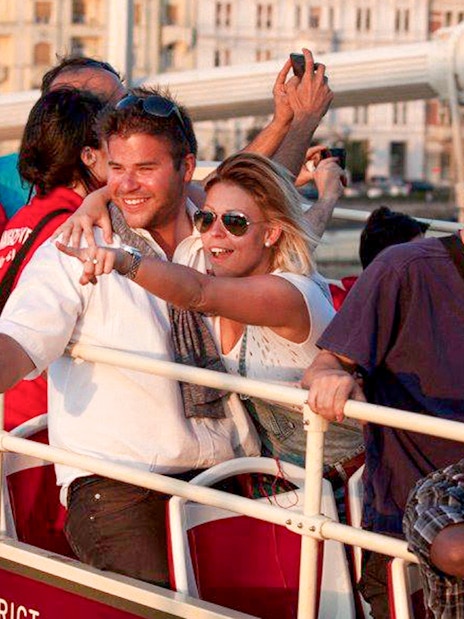 Tourists enjoying Budapest Big Bus tour near Hungarian Parliament and Danube River.