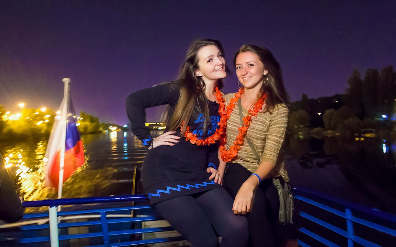 Two people enjoying a night boat party on the Vltava River in Prague.
