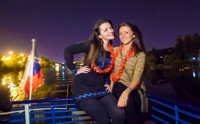 Two people enjoying a night boat party on the Vltava River in Prague.