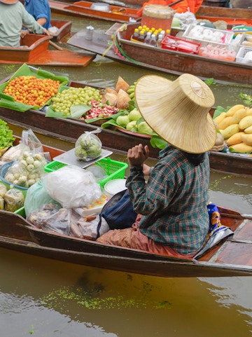 Vendor selling fruits from a boat at Bangkok Floating Market.