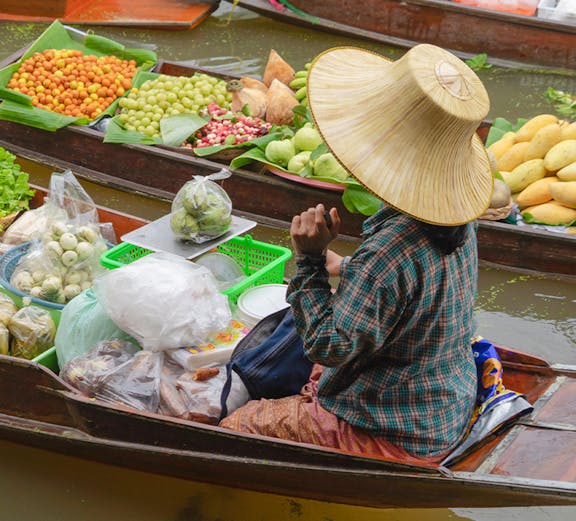 Vendor selling fruits from a boat at Bangkok Floating Market.