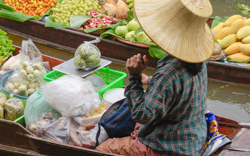 Vendor selling fruits from a boat at Bangkok Floating Market.