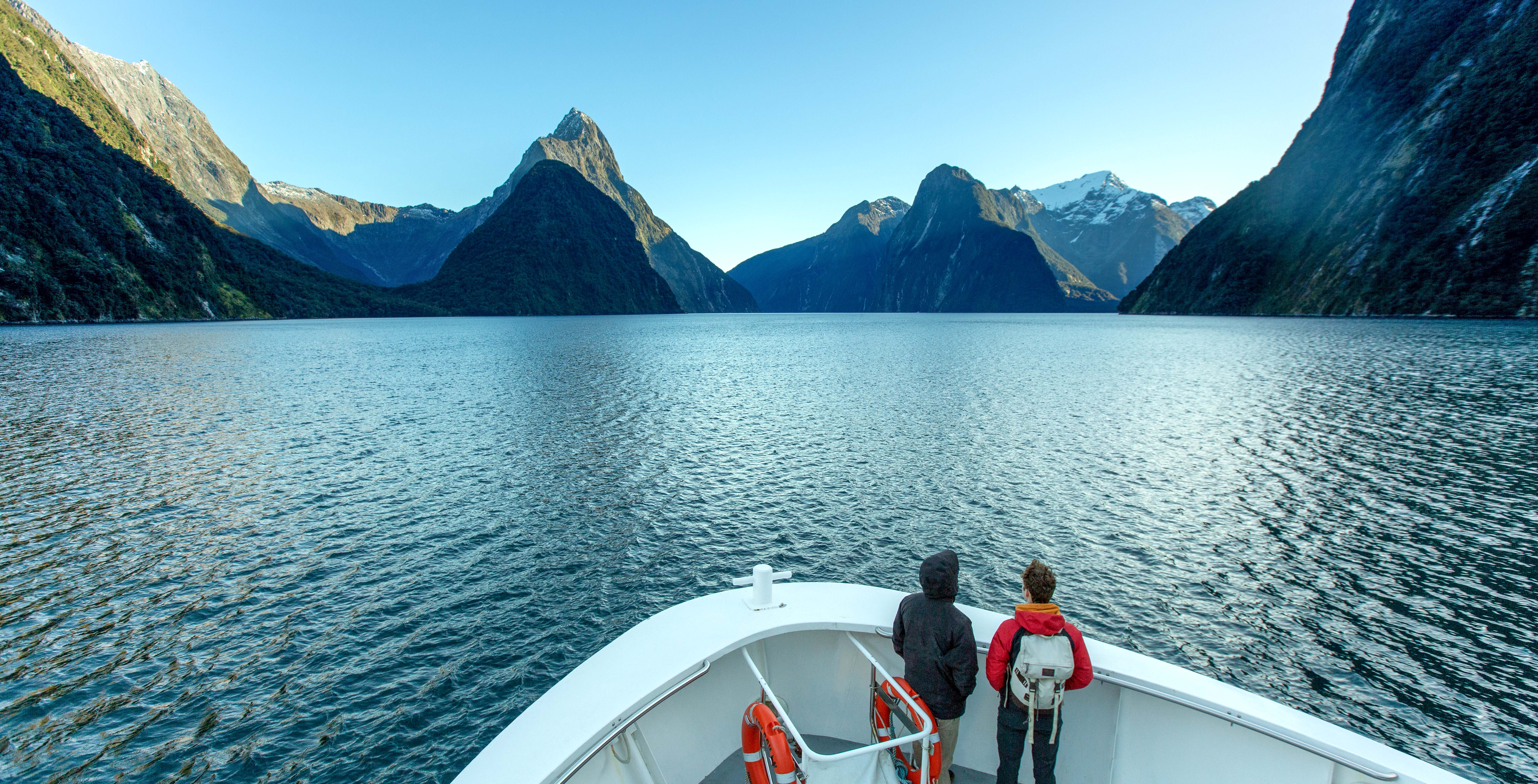 People enjoying a scenic cruise on Doubtful Sound, Queenstown, surrounded by lush mountains.