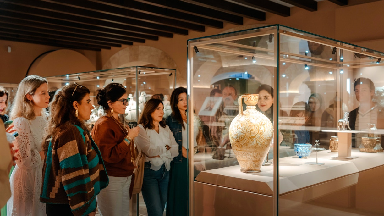 Visitors observing ornate pottery at Abu Dhabi Royal Equestrian Arts exhibit.