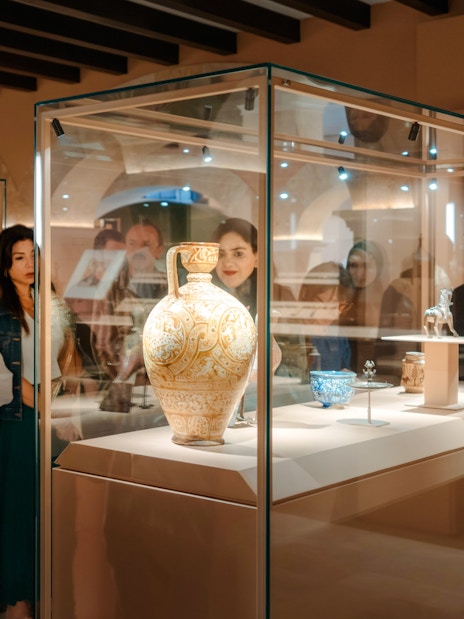Visitors observing ornate pottery at Abu Dhabi Royal Equestrian Arts exhibit.